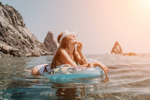 Woman summer sea. Happy woman swimming with inflatable donut on the beach in summer sunny day, surrounded by volcanic mountains. Summer vacation concept