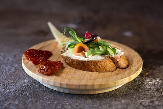 A delicious and healthy open-faced sandwich with cream cheese, smoked salmon, microgreens, and sun-dried tomato on a wooden board. Perfect for a light lunch or snack. Isolated on white background.