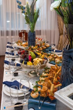 An elegant spread of delectable treats and floral arrangements on a beautifully set dining table, creating a sophisticated and refined ambiance for a special occasion.