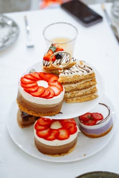 An elegant display of cakes and pastries on a three-tiered stand with a glass of orange juice. The image exudes indulgence and sophistication, perfect for a high-end bakery or cafe.