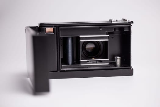 A vintage black and silver retro camera with an open back, revealing a film roll. This classic 1970s camera captures the nostalgia of analog photography, evoking timeless beauty and vintage charm.