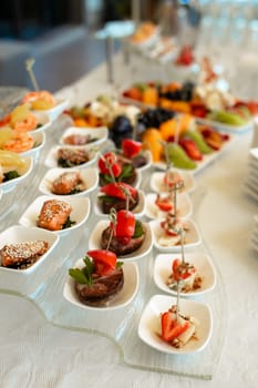 A diverse spread of appetizers and refreshing beverages awaits at this elegant catering buffet. Enjoy fresh fruits, delectable pastries, and flavorful sandwiches for a delightful dining experience.