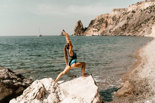 Yoga on the beach. A happy woman meditating in a yoga pose on the beach, surrounded by the ocean and rock mountains, promoting a healthy lifestyle outdoors in nature, and inspiring fitness concept