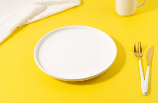 Empty white plate on a yellow background.