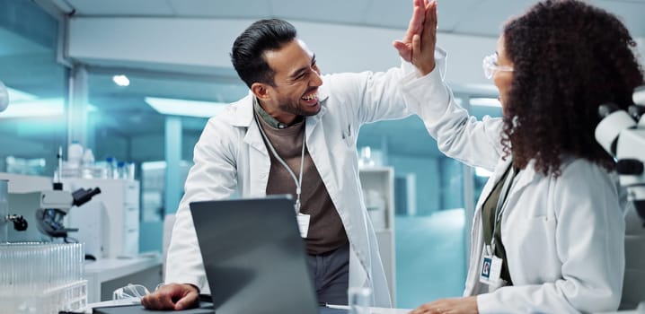 Scientist, teamwork and high five with laptop in laboratory for test breakthrough, pharmaceutical review or success. Science, collaboration or technology for research, discussion and digital analysis.