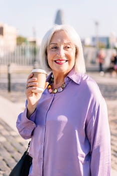 portrait of a smiling senior woman with a takeaway coffee, concept of elderly people leisure and active lifestyle