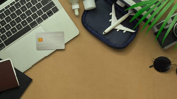 Above view of airplane model, passport, camera, credit card, sunglasses on table. Traveling concept.