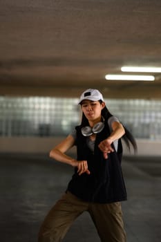 Young woman hip hop dancer dancing with passion and energy in a dark parking garage.