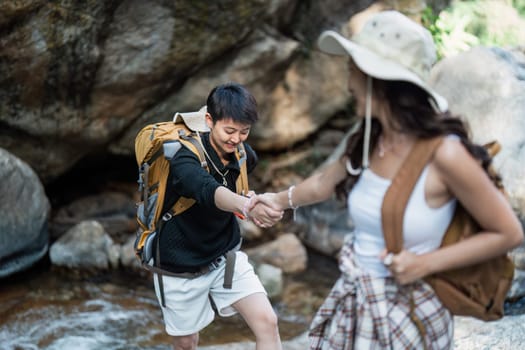 Happy LGBT Lesbian couple Travelers Hiking with Backpacks in waterfall Trail. LGBT Lesbian Couple Hikers with backpacks walks in mountains in vacation.