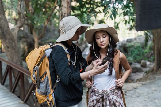 Happy LGBT Lesbian couple Travelers Hiking with Backpacks in waterfall Trail. LGBT Lesbian Couple Hikers with backpacks walks in mountains in vacation.