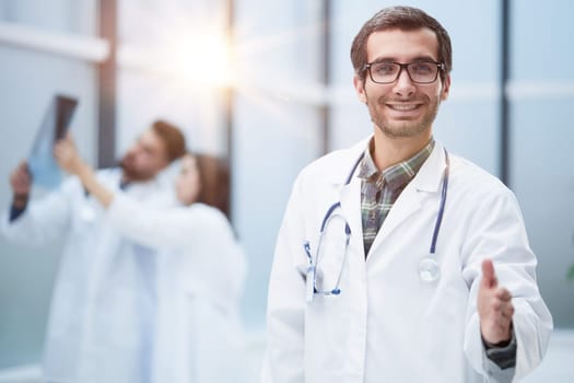 image of a doctor extending his hand in greeting against the background of his colleagues