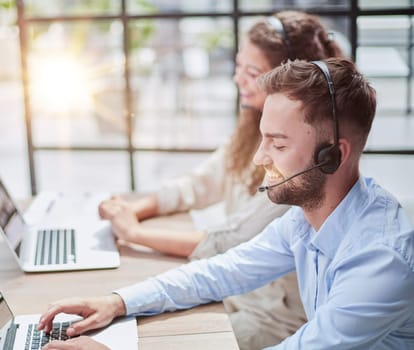 Handsome male customer service agent working in call center office as a telemarketer.