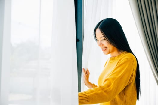 A young woman opens the curtains in the early morning smiles at the pleasant view feeling refreshed and joyful at home. Embracing morning happiness relaxation and a cheerful start.