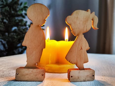 Wooden toys of boy and girl with yellow candles. Couple in love on Valentine's Day. Celebration of love and friendship. Card, background