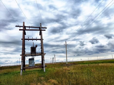 Old power poles and the sky with clouds in the background. Electric lines, towers, wires in landscape