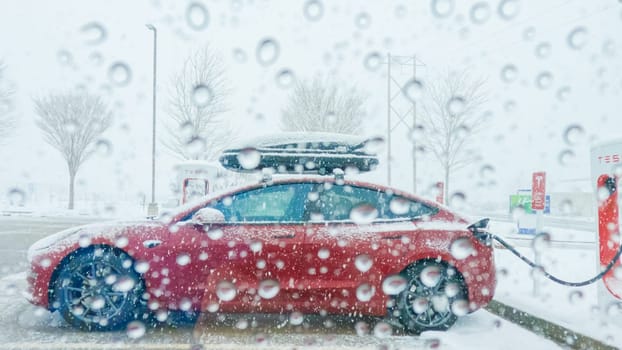 Denver, Colorado, USA-December 7, 2022--POV-During a wintry journey through Western Colorado, a Tesla electric car makes a stop at a Supercharger station.