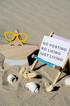 NO POSTING NO LIKING JUST LIVING text on paper greeting card on background of beach chair lounge starfish summer vacation decor. Concept of social media technology detox Sandy beach sun. Holiday postcard. Travel Business concept