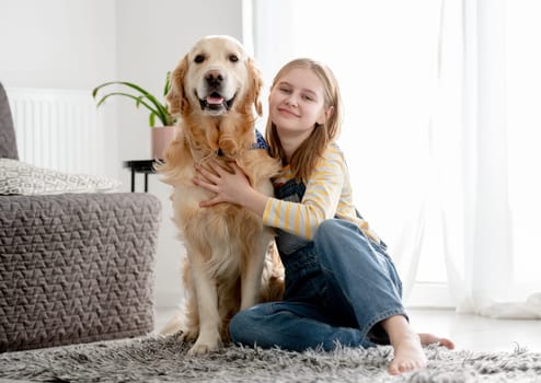 Girl With Golden Retriever Dog Poses At Home On Floor For A Portrait With Dog