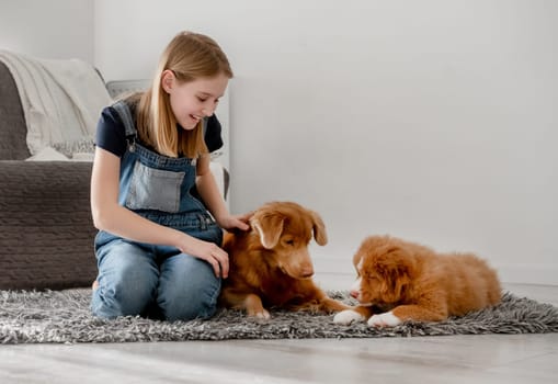 11-Year-Old Girl Plays With Nova Scotia Retriever And Its Puppy At Home On The Floor, Nova Scotia Retriever Toller