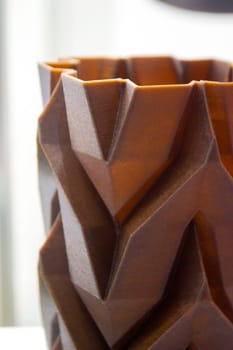 Art object vase printed on 3D printer from melted brown plastic with addition waste coffee. Model made of plastic with spent coffee by 3d printer. Additive progressive technology 3D printing recycling