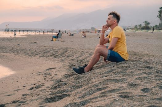 Man sits on the beach and looks at the sea in Alanya city, Turkey. Travelling or vacation concept