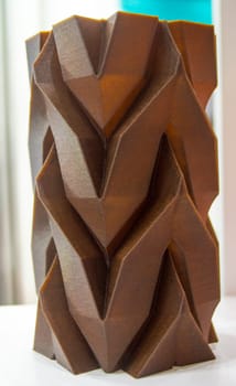 Art object vase printed on 3D printer from melted brown plastic with addition waste coffee. Model made of plastic with spent coffee by 3d printer. Additive progressive technology 3D printing recycling