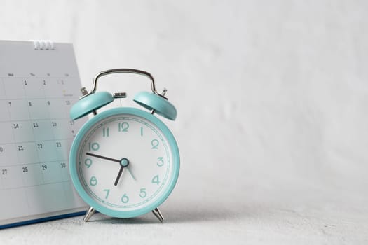 The alarm clock and calendar positioned on a white background symbolize dates, time, planning, and appointments.