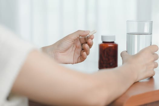 Hand holding a glasses of drinking water with taking pills, emphasizing healthcare and medication