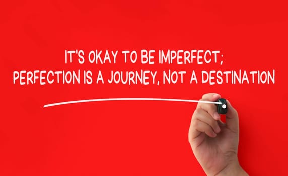 Hand writing It is okay to be imperfect affirmation on red cover background. Affirmation concept