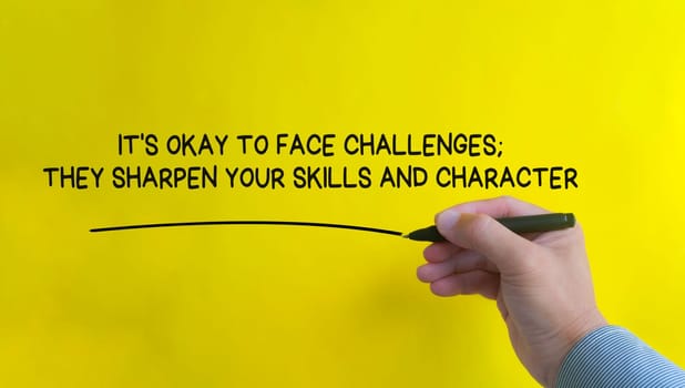 Hand writing It is okay to face challenges affirmation on yellow cover background. Affirmation concept