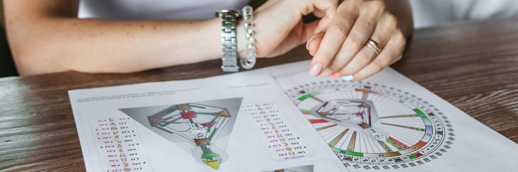 Tver, Russia - August 2, 2021. A woman in a cafe at a table is studying the design of a person. The concept of studying esoteric sciences. A bodigraph or a map of a person on an A4 sheet.