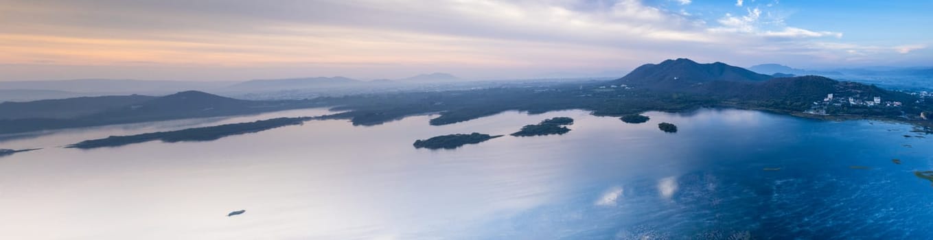 Aerial drone panoramic shot showing sunrise dawn dusk over aravalli hills lake pichola fateh sagar and cityscape in Udaipur, Chandigarh, Nainital showing famous tourist spot in India