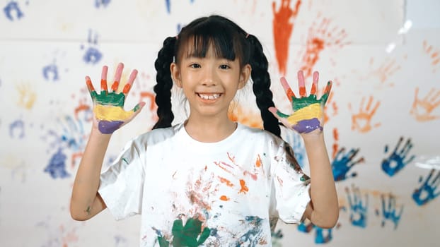 Asian happy student put hands up together show colorful stained hands. Smiling girl standing in front white background with stained hands while looking at camera. Creative activity concept. Erudition.