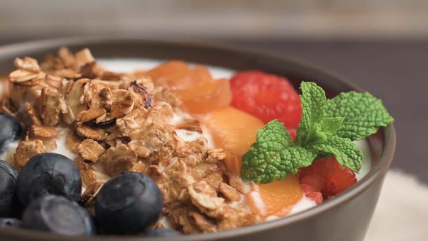 Yogurt with baked granola and berries in small bowl strawberries blueberries. Granola baked with nuts and honey for little sweetness. Slide from left.