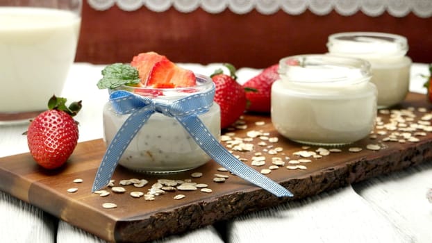 Strawberries desert with cream and cereals served on glass cups over table top.