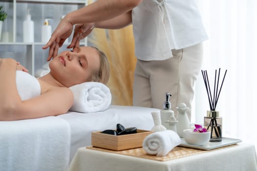 Caucasian woman enjoying relaxing anti-stress head massage and pampering facial beauty skin recreation leisure in dayspa modern light ambient at luxury resort or hotel spa salon. Quiescent