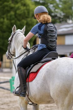 Rider in protective corset for the spine on a white horse