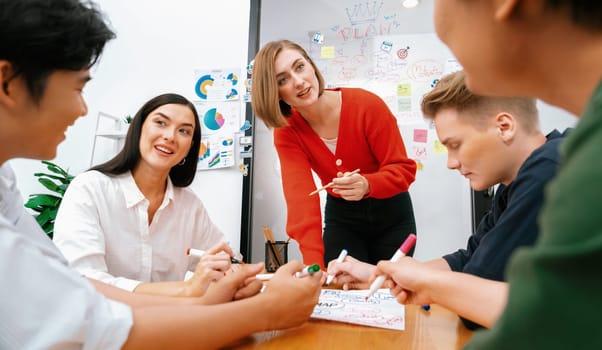 Creative happy business team brainstorming and sharing idea by using mind map and graphic graph while young beautiful project manager pointing at important point at business meeting. Immaculate.