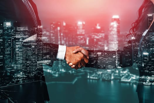 Double exposure image of business people handshake on city office building in background show partnership success of business deal. Concept of corporate teamwork, trust partner and work agreement. uds