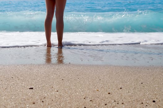 bare feet of a girl in sea water on the beach.