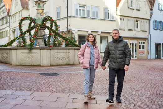 Loving couple of tourists walking around old town. Man woman couple walking europe old town Germany. Couple of lovers leisurely stroll in the cool autumn morning on the streets of a BIETIGHEIM-BISSINGEN (Germany). The guy holds his wife. Vacation, autumn, holiday. Couple Walking in Europe's Old Town