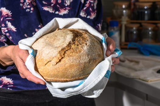 Woman holding homemade whole grain bread in her hands