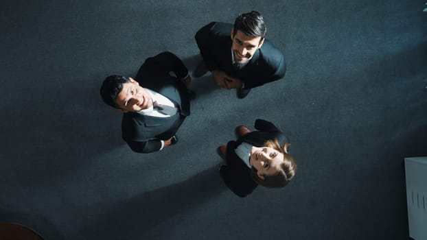 Top down aerial view of happy multicultural business team looking up at ceiling while standing and looking at camera in meeting room. Group of smart people brainstorming and discuss plan. Directorate.