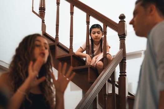 Stressed and unhappy young girl watch her parent arguing from the stair. Domestic violence at home and traumatic childhood develop to depression and anxiety. Unhealthy family concept. Synchronos