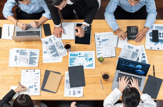 Panorama top view diverse group of business analyst team analyzing financial data report paper on meeting table. Chart and graph dashboard by business intelligence analysis. Meticulous