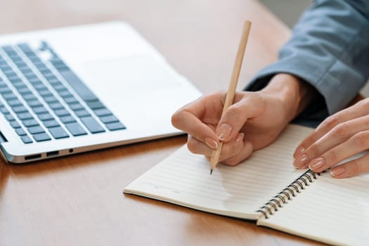 Businesswoman taking note while working on business on workspace table. Young college student study writing or brainstorming strategic plan in office workplace for business success. Blithe