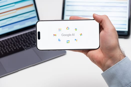 PRAGUE, CZECH REPUBLIC - JANUARY 21 2024: Google AI logo on the screen of a cell phone in business mans hand and laptop on the background.