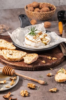 Brie type of cheese. Camembert cheese. Fresh sliced Brie cheese on a wooden tray with nuts, honey and leaves. Italian, French cheese.