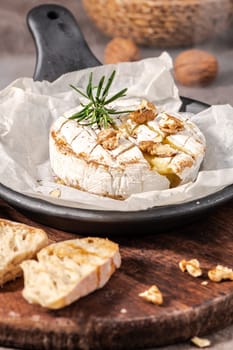 Brie type of cheese. Camembert cheese. Fresh sliced Brie cheese on a wooden tray with nuts, honey and leaves. Italian, French cheese.