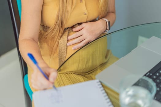 Beautiful pregnant woman working on laptop. Young businesswoman working in her office.